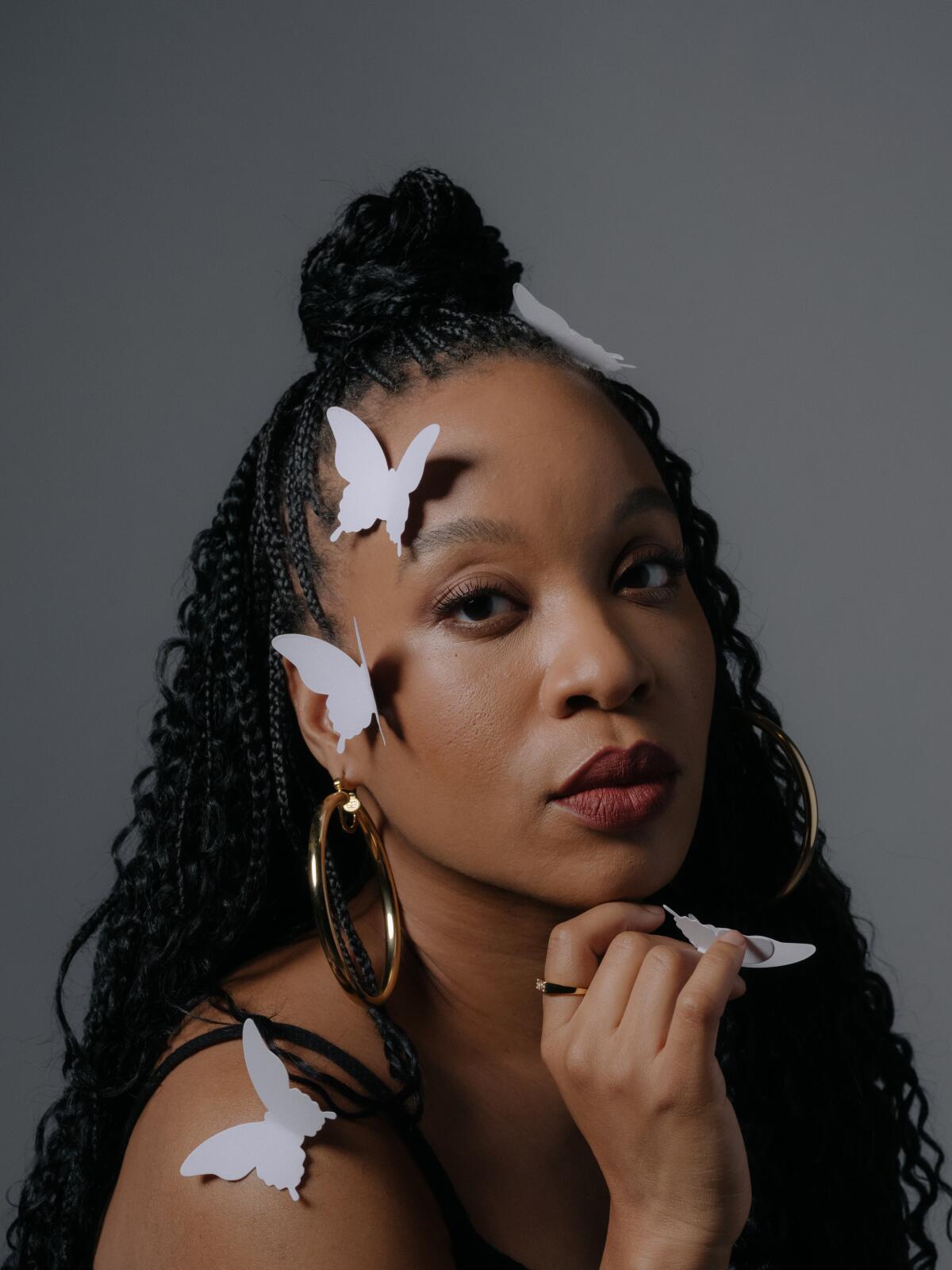 A woman poses for a tight portrait with a string of butterflies draped in her hair.