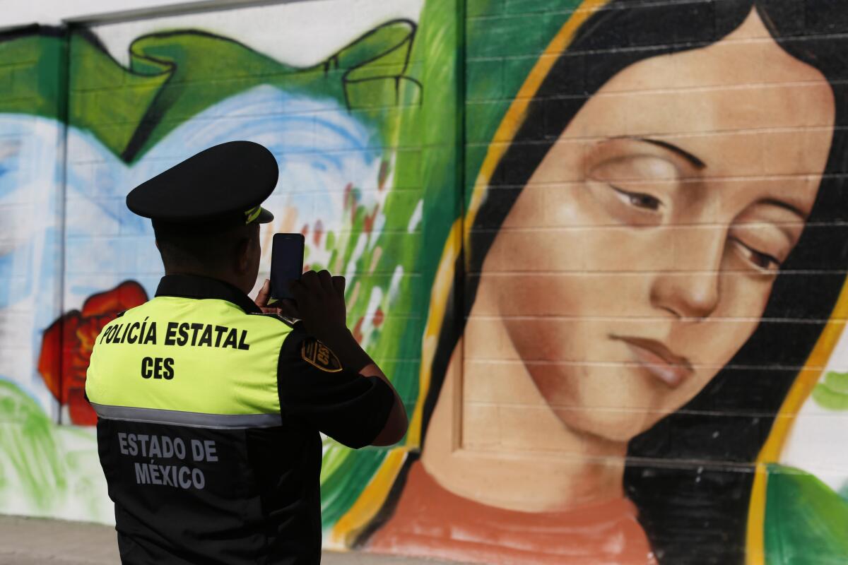 Un policía toma una foto de un mural de la Virgen de Guadalupe en el barrio de Ecatepec de la Ciudad de México. El papa visitará la Basílica de la Virgen de Guadalupe durante su viaje a México. (AP Photo/Dario Lopez-Mills, File)