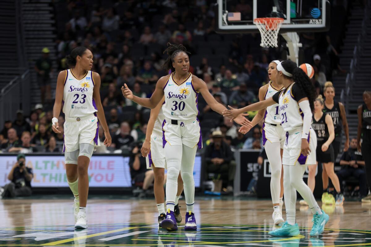 Sparks forward Nneka Ogwumike (No. 30) slaps hands with teammate Jordin Canada during a win over the Storm on Sunday.