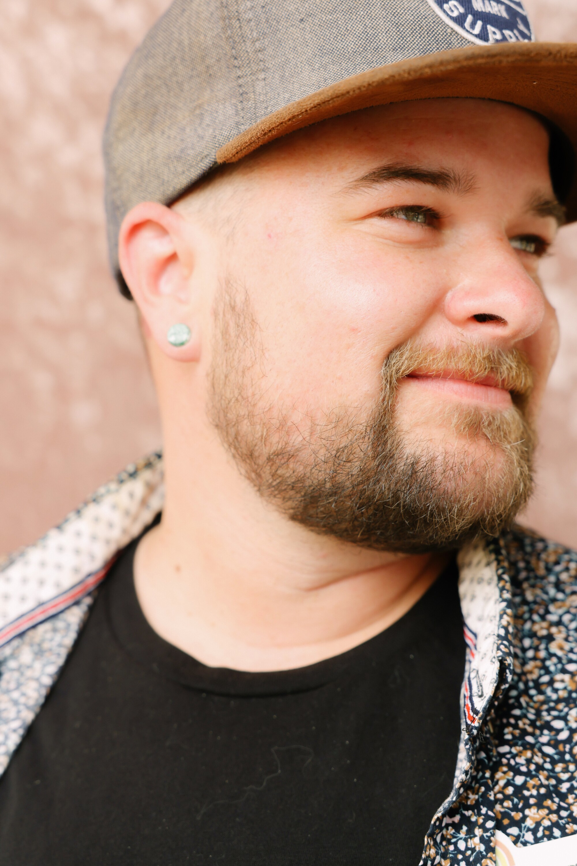 A person with a beard and a baseball hat poses for a portrait.