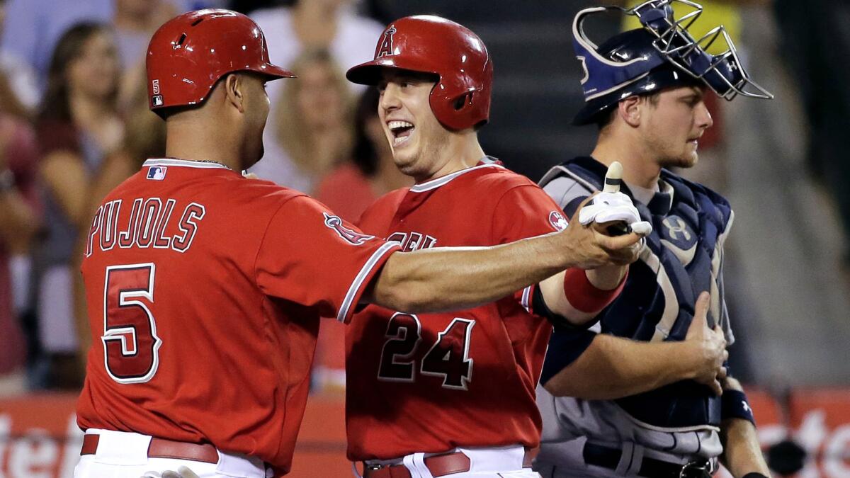 Angels first baseman C.J. Cron (24) celebrates at home plate with designated hitter Albert Pujols after hitting a two-run home run in the seventh inning Friday night in Seattle.