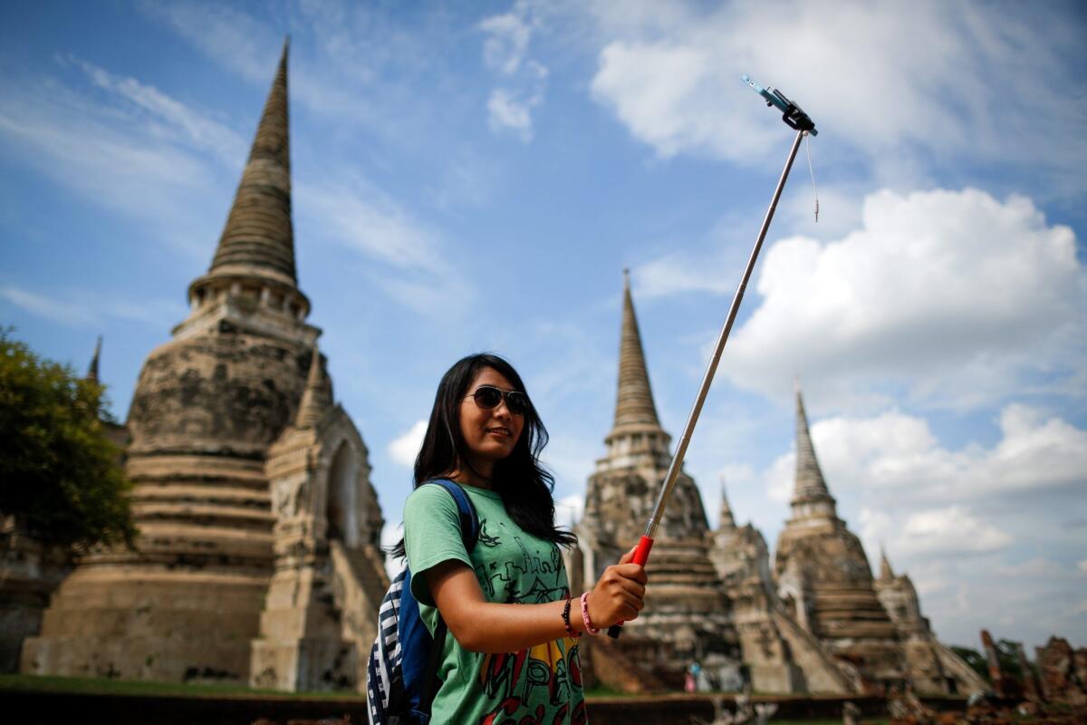 A tourist uses a selfie stick to take a photo of herself in the ancient historical city of Ayutthaya, north of Bangkok, Thailand, on Aug. 11, 2015.