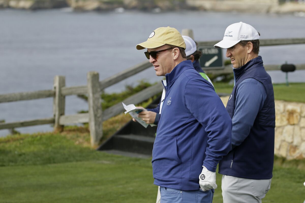 Peyton Manning, left, and brother Eli  look over the seventh green of the Pebble Beach Golf Links in 2020.  
