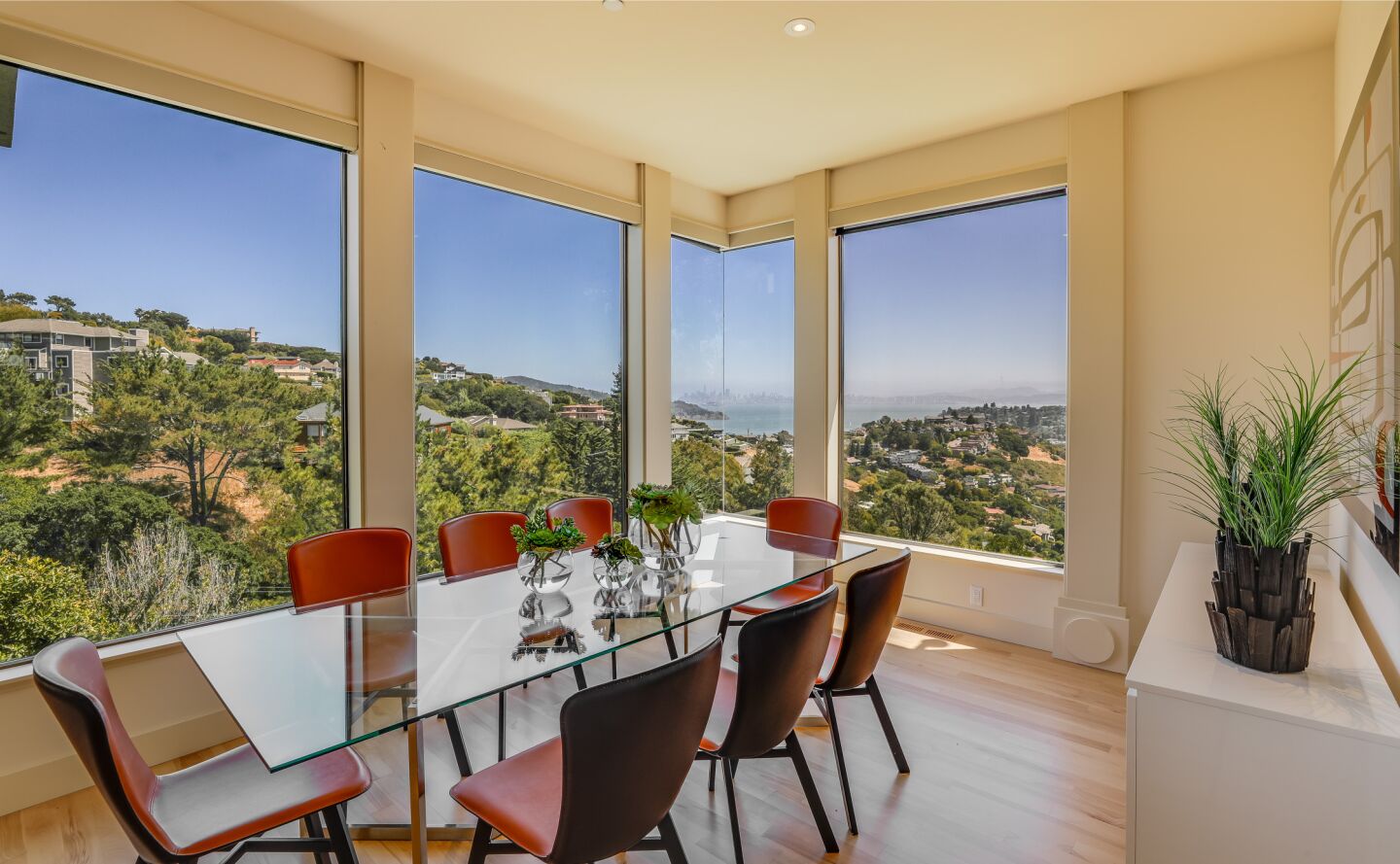 A dining table sits alongside large windows.