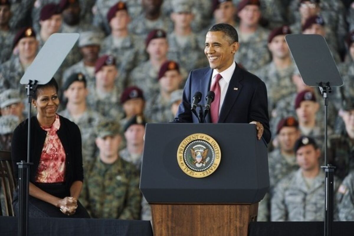 President Obama speaks as First Lady Michelle Obama listens during a tribute to the troops at Ft. Bragg, N.C.