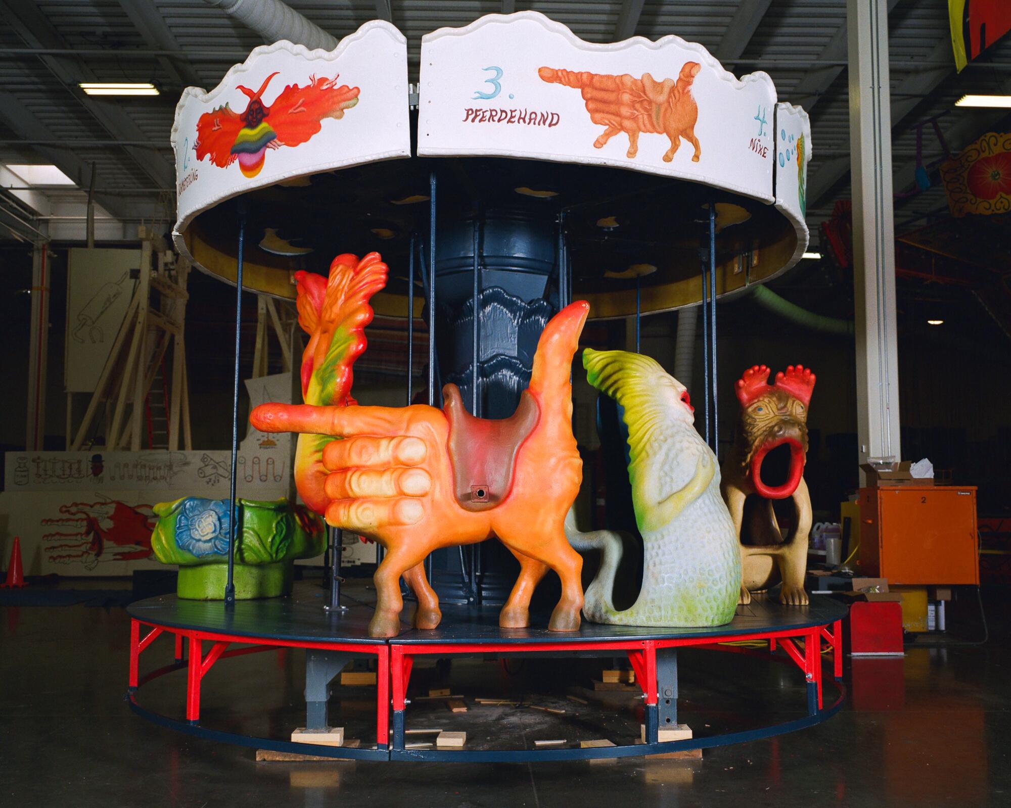 Arik Brauer's carousel features a striking, giant orange hand in a trigger position. 