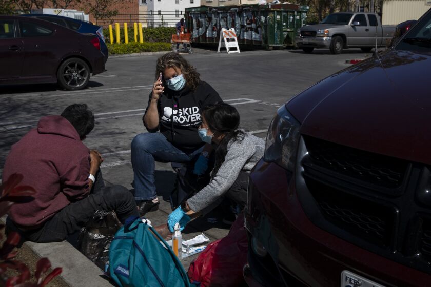 LOS ANGELES, CALIF. - MARCH 26: (*Editor's Note: Upcoming Story by Steve Lopez) During the Coronavirus Dr. Susan Partovi, MD middle, and nurse practitioner Jen King, right, administers medical aid to a man in the Home Depot parking lot in Los Angeles, Calif. on Thursday, March 26, 2020. (Francine Orr / Los Angeles Times)