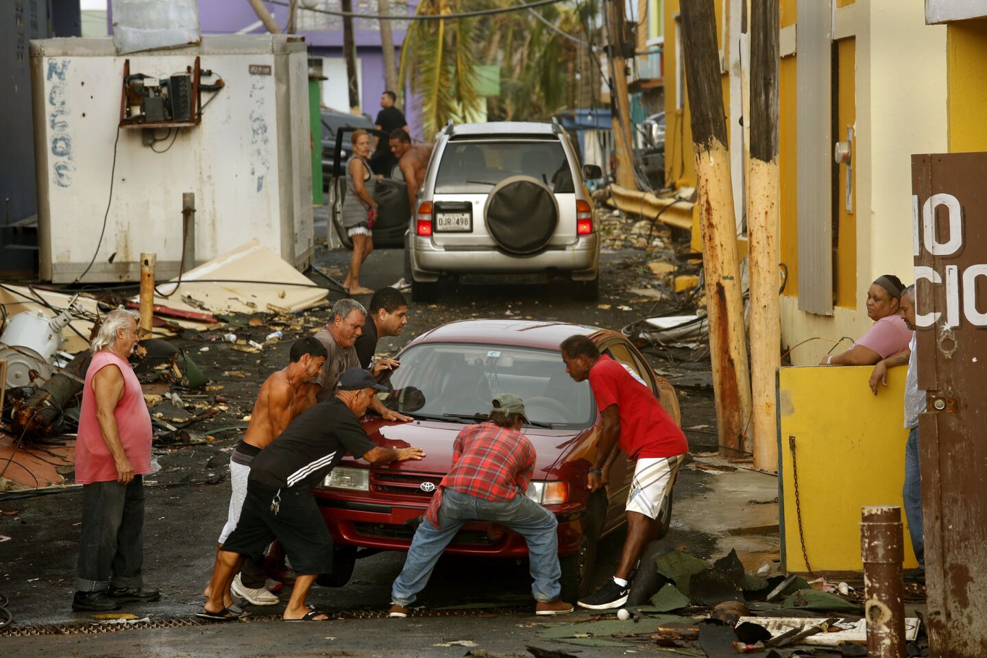 Neighbors come together to move a car in San Juan's La Perla area.
