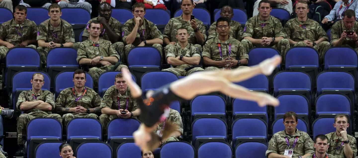 British soldiers watch gymnast Simona Castro Lazo from Chile perform during the Artistic Gymnastics women's qualification at the 2012 Summer Olympics on Sunday in London. Troops, teachers and students are getting free tickets to fill prime seats that were empty at some Olympic venues on the first full day of competition.