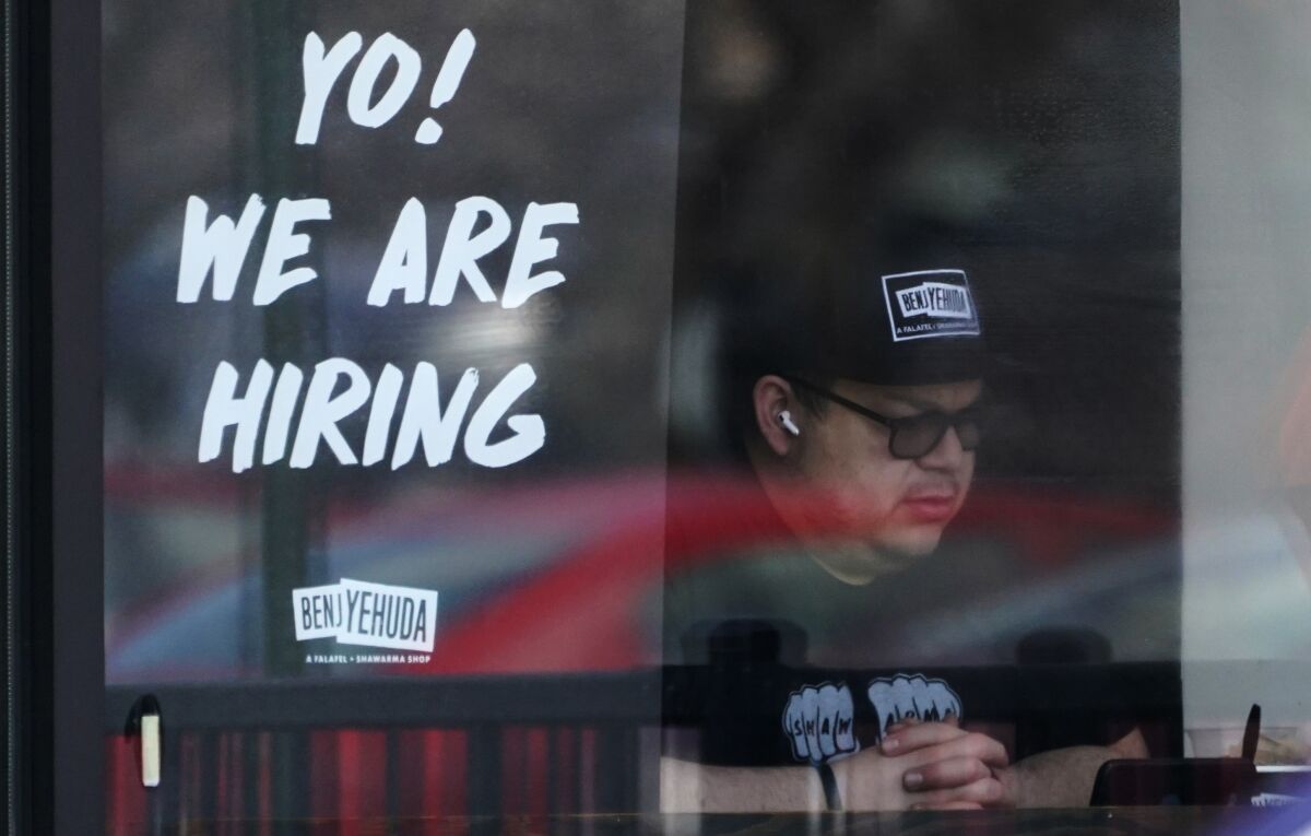 A hiring sign is displayed at a restaurant