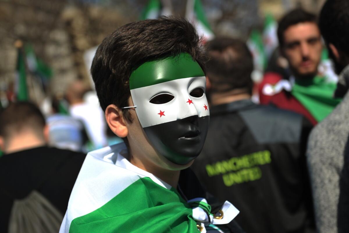 The U.S. on Tuesday ordered Syria to close its embassy in Washington. Above, a demonstrator wearing a mask depicting a Syrian opposition flag during an anti-Assad rally Saturday in Washington.