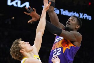 El pívot de los Suns de Phoenix Deandre Ayton lanza el balón sobre el alero del Jazz de Utah Lauri Markkanen en el encuentro del sábado 26 de noviembre del 2022. (AP Foto/Rick Scuteri)