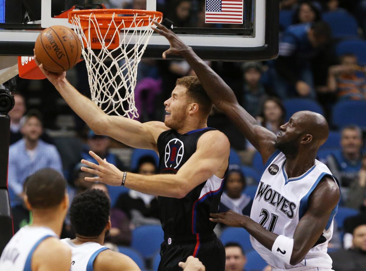 Clippers forward Blake Griffin (32) uses the rim to protect his reverse layup attempt from Timberwolves forward Kevin Garnett's (21) block attempt.