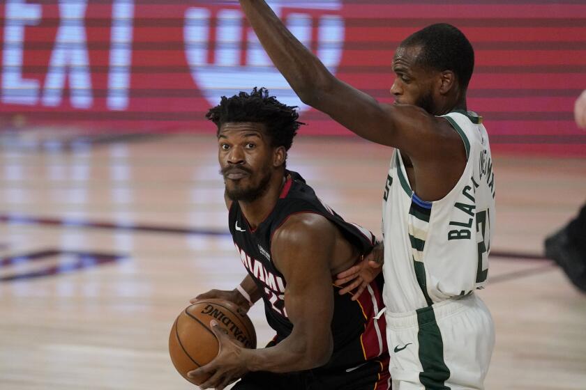 Miami Heat's Jimmy Butler, left, drives against Milwaukee Bucks' Khris Middleton (22) in the first half of an NBA conference semifinal playoff basketball game Tuesday, Sept. 8, 2020 in Lake Buena Vista, Fla. (AP Photo/Mark J. Terrill)