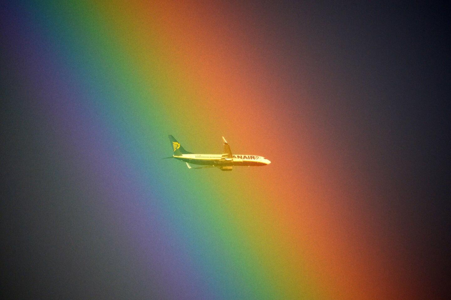 A Ryanair plane flies in front of a rainbow over Rome.