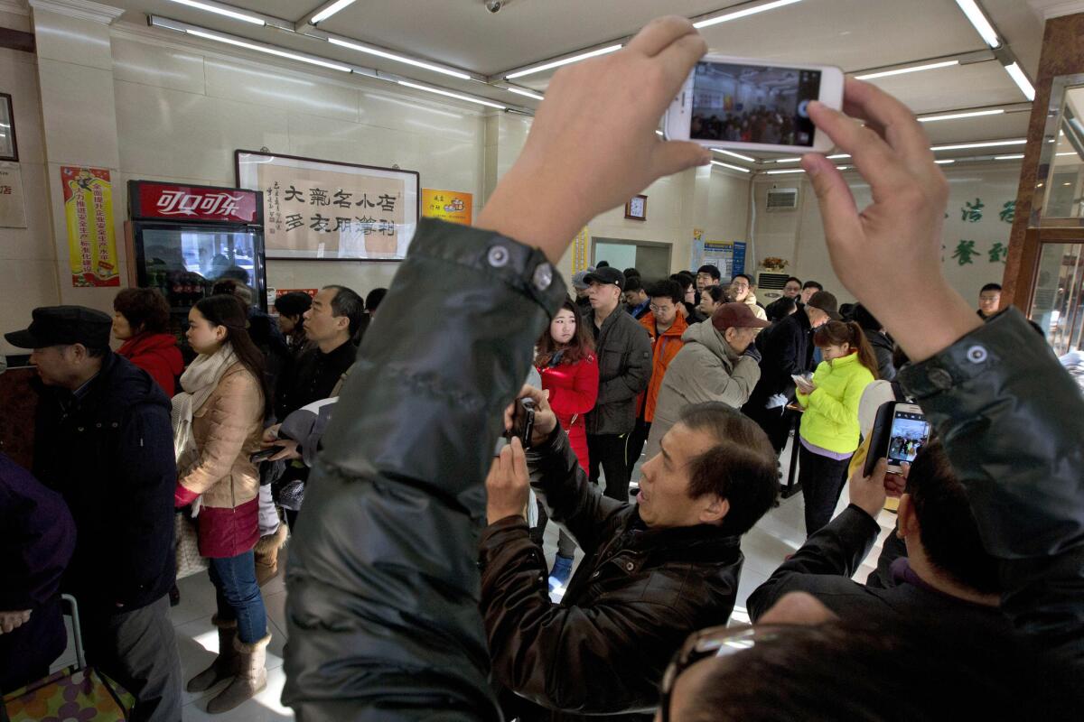 Smartphone users take photos in a Beijing restaurant where President Xi Jinping lined up the day before to order a simple lunch of steamed buns, vegetables and stewed pig intestines.