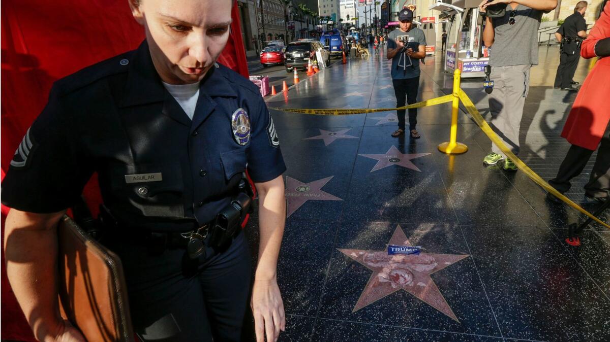 Una agente de la policía investiga los daños a la estrella del candidato presidencial Donald Trump en el Paseo de la Fama de Hollywood.
