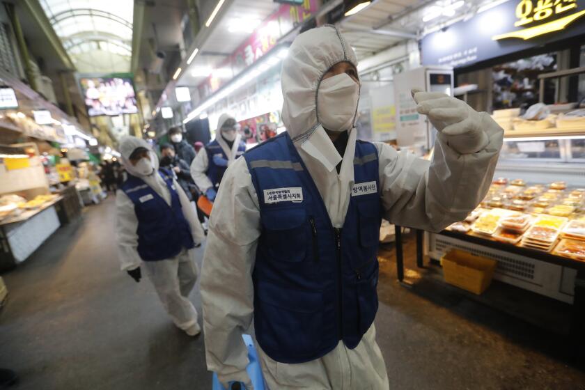 Workers wearing protective gears arrive to spray disinfectant as a precaution against the coronavirus at a market in Seoul, South Korea, Monday, Feb. 24, 2020. South Korean President Moon Jae-in said his government had increased its anti-virus alert level by one notch to “Red,” the highest level. It allows for the temporary closure of schools and reduced operation of public transportation and flights to and from South Korea. (AP Photo/Ahn Young-joon)