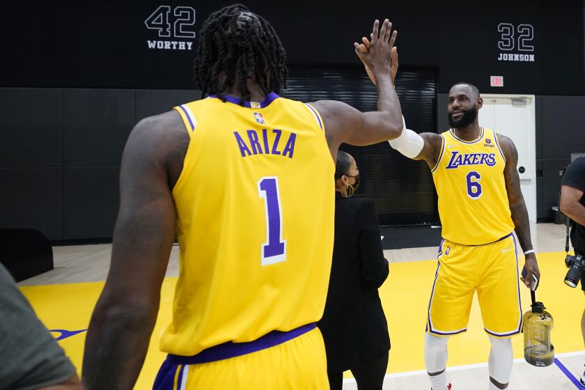 Los Angeles Lakers forward LeBron James, right, high-fives teammate Trevor Ariza during the NBA basketball team's Media Day Tuesday, Sept. 28, 2021, in El Segundo, Calif. (AP Photo/Marcio Jose Sanchez)