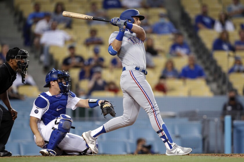 The Rangers' Nate Lowe follows through on an RBI single in the third inning as Dodgers catcher Will Smith looks on.