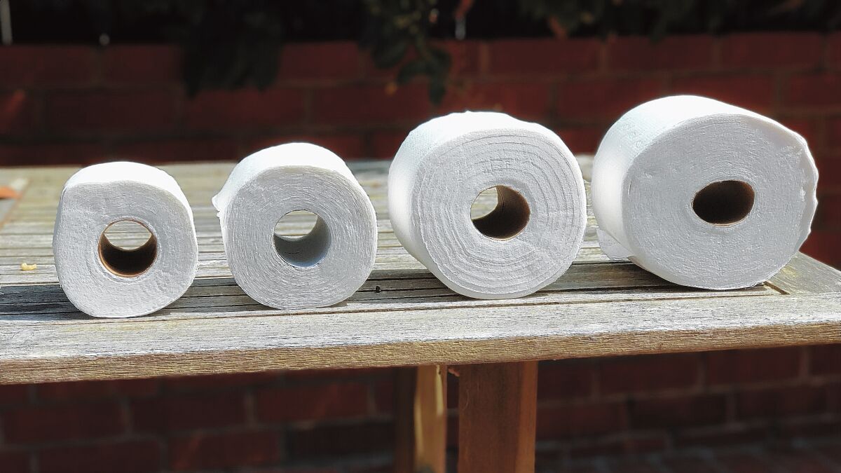 Four rolls of toilet paper lined up on a table in ascending order of size