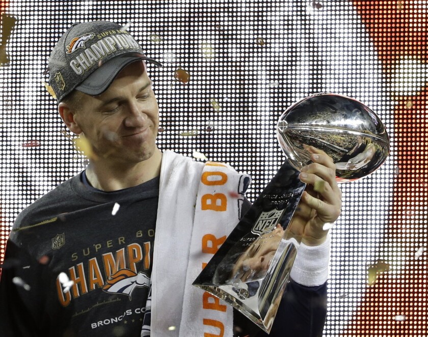 Broncos quarterback Peyton Manning looks at the Vince Lombardi Trophy during the Super Bowl 50 awards ceremony following Denver's 24-10 victory over the Carolina Panthers.