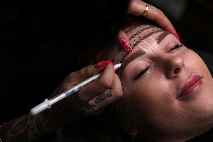 LOS ANGELES, CALIFORNIA-FEBRUARY 12, 2020: Kahli Smith, left, draws lines before microblading Tess Henderson's, right, eyebrows at Fiction Cosmetic Tattooing on February 12, 2020, in Los Angeles, California. (Photo By Dania Maxwell / Los Angeles Times)