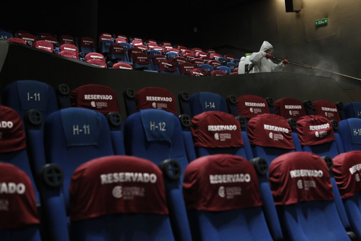 A worker disinfects a theater after a movie screening, at the Cineteca Nacional, Mexico's film archive, in Mexico City, Wednesday, Aug. 12, 2020. After being closed for nearly five months amidst the ongoing coronavirus pandemic, movie theaters in the capital reopened Wednesday at 30% capacity.(AP Photo/Rebecca Blackwell)