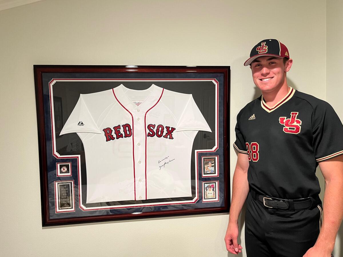 JSerra player Dominic Smaldino poses next to a framed Red Sox uniform.