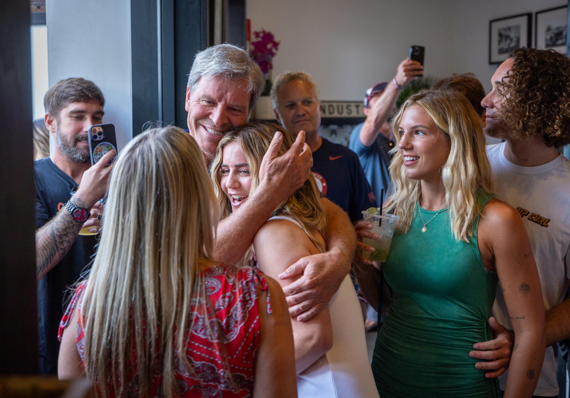 U.S. Olympic surfing team member Caroline Marks, center, gets a hug from a fan.