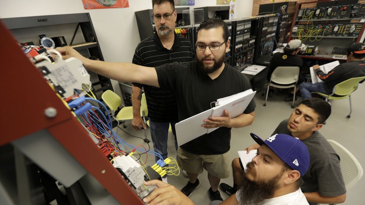 Steve Nagy, left, an industrial electrical instructor, watches as students John Hernandez, Eduardo Venegas and Joel Paz troubleshoot an electrical problem at InTech Center's Industrial Electrical Laboratory.