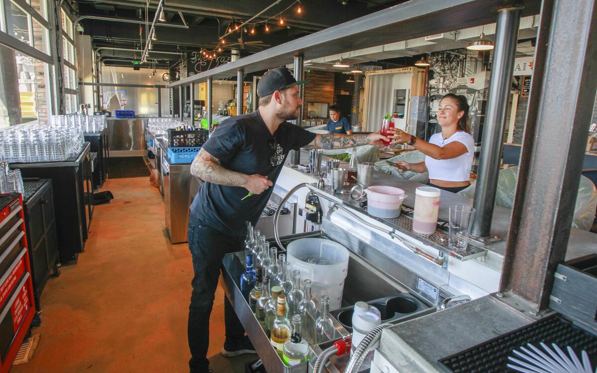 Beverage director Jesse Ross, left, and general manager Ali DeLaune, right, go over some last-minute drink adjustments at the new Windmill Food Hall on Thursday in Carlsbad, California. Restaurateur James Markham is behind the renovation of the iconic North County building. The project will open on Labor Day weekend.