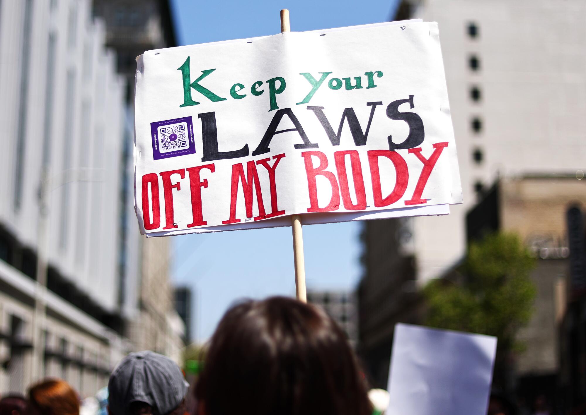 A protester holds up a sign reading "Keep your laws off my body."