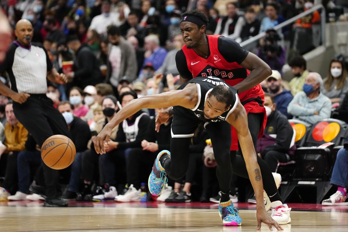 Toronto Raptors forward Pascal Siakam, top, picks up a foul on Brooklyn Nets forward Kevin Durant as they fight for the ball during second-half NBA basketball game action in Toronto, Sunday, Nov. 7, 2021. (Frank Gunn/The Canadian Press via AP)