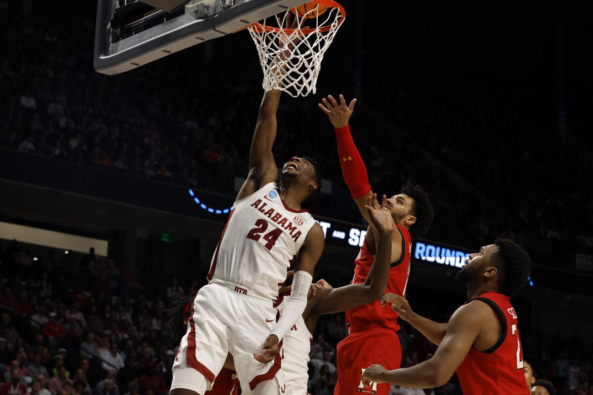 Alabama forward Brandon Miller (24) lays in a basket as Maryland forward Patrick Emilien, center, defends in the first half of a second-round college basketball game in the NCAA Tournament in Birmingham, Ala., Saturday, March 18, 2023. (AP Photo/Butch Dill)