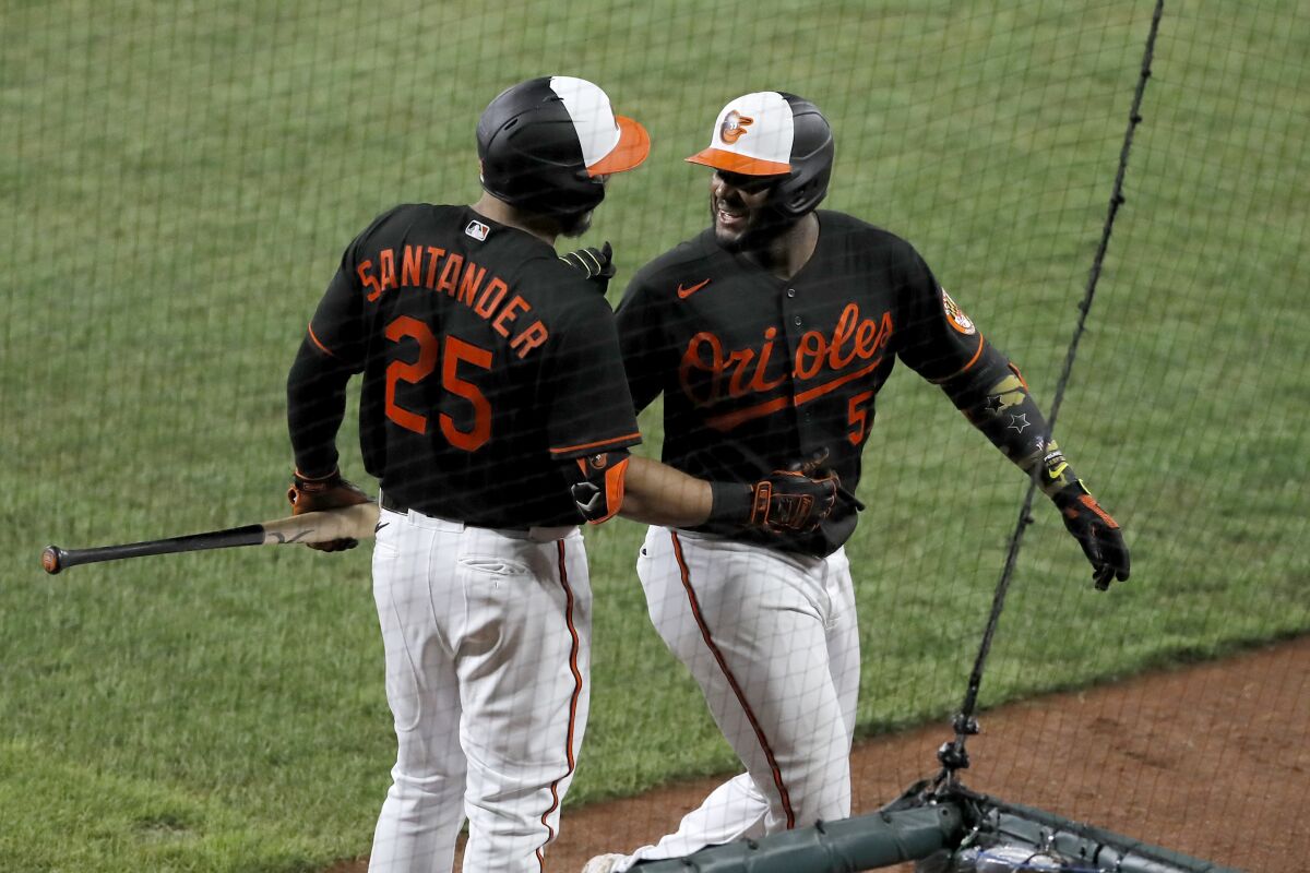 Baltimore Orioles' Hanser Alberto, right, talks with Anthony Santander (25) after hitting a solo home run off Tampa Bay Rays relief pitcher Ryan Thompson during the eighth inning of a baseball game, Friday, July 31, 2020, in Baltimore. (AP Photo/Julio Cortez)