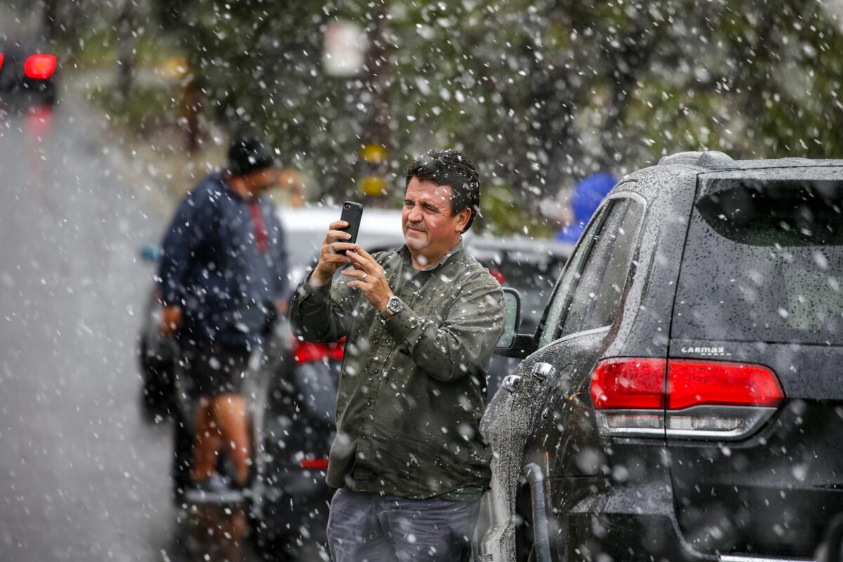 Manuel Carrera, 57, photographs falling snow on Haven Avenue in Rancho Cucamonga on Thursday.