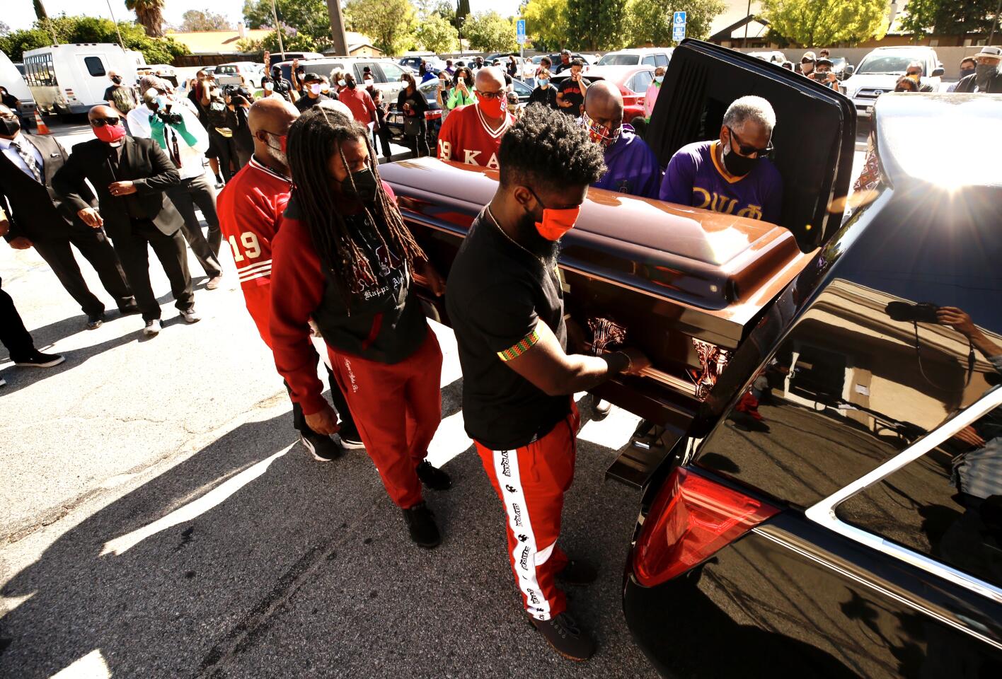 People place an empty casket in memory of George Floyd into a hearse at Reseda Church of Christ.