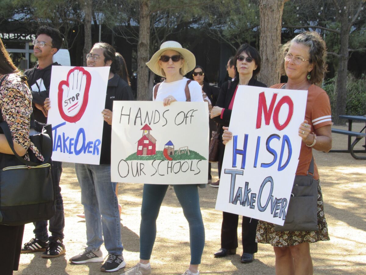 People hold up signs at a news conference on Friday, March 3, 2023, in Houston while protesting the proposed takeover of the city's school district by the Texas Education Agency. Local and federal officials say state leaders are preparing to take over the Houston Independent School District over allegations of misconduct by district board members and the yearslong failing performance of one campus. ( Juan A. Lozano/AP Photo)