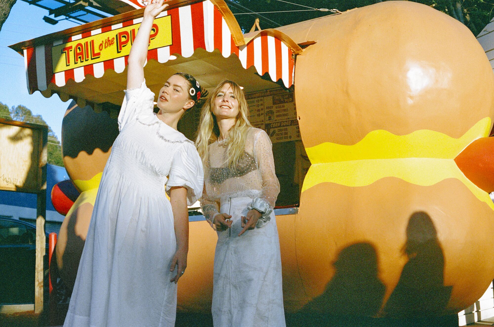 Two women in front of a hot dog stand