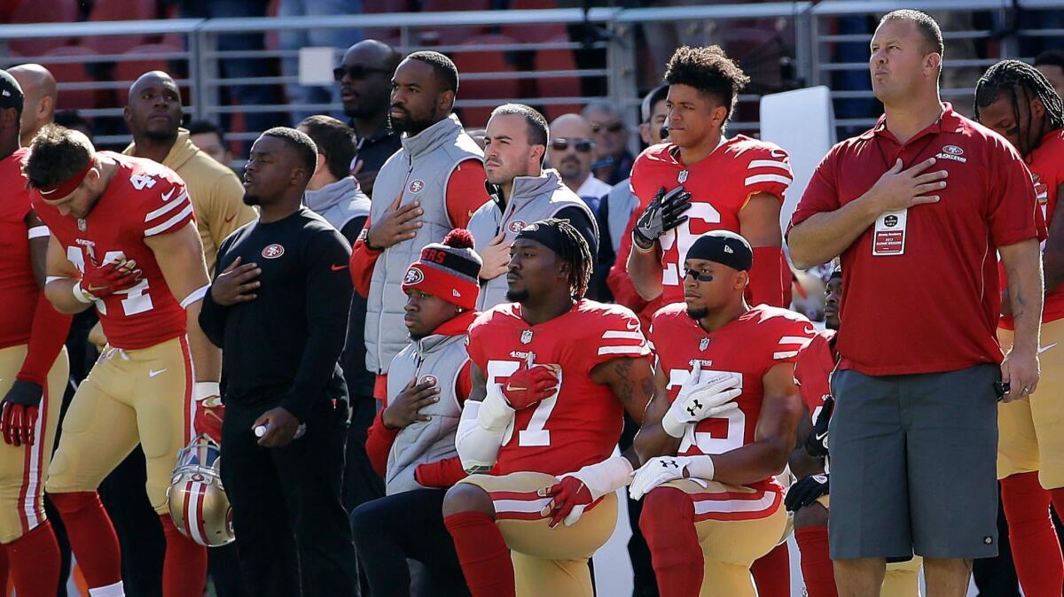 San Francisco 49ers outside linebacker Eli Harold, bottom center, and safety Eric Reid, bottom right, kneel during the national anthem before a Nov. 5 NFL football game against the Arizona Cardinals in Santa Clara.