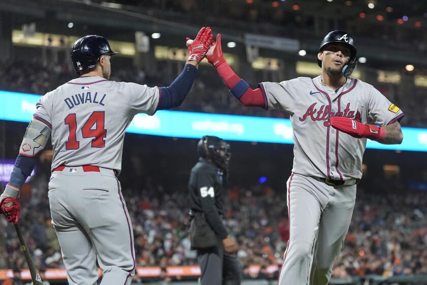 Orlando Arcia, derecha, de los Bravos de Atlanta, es felicitado por Adam Duvall (14) después de anotar la carrera de la diferencia en contra de los Gigantes de San Francisco durante la 10ma entrada del juego de béisbol del lunes 12 de agosto de 2024, en San Francisco. (AP Foto/Jeff Chiu)