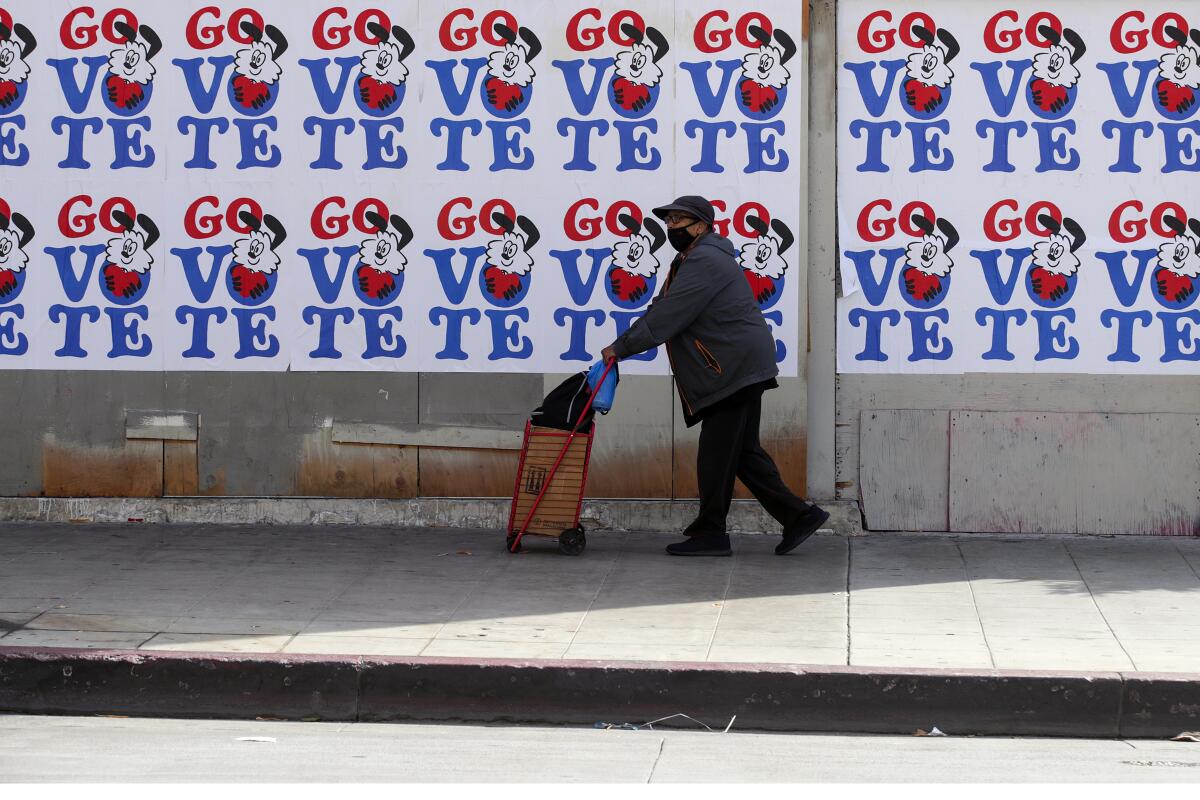 A man walks past a Go Vote mural on Broadway in front of Grand Central Market in 2020