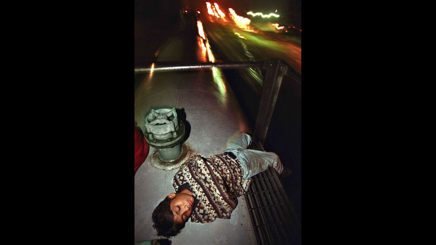 Denis sleeps atop a fuel car speeding through a pueblo in Chiapas, his left leg around a railing to keep from falling off.