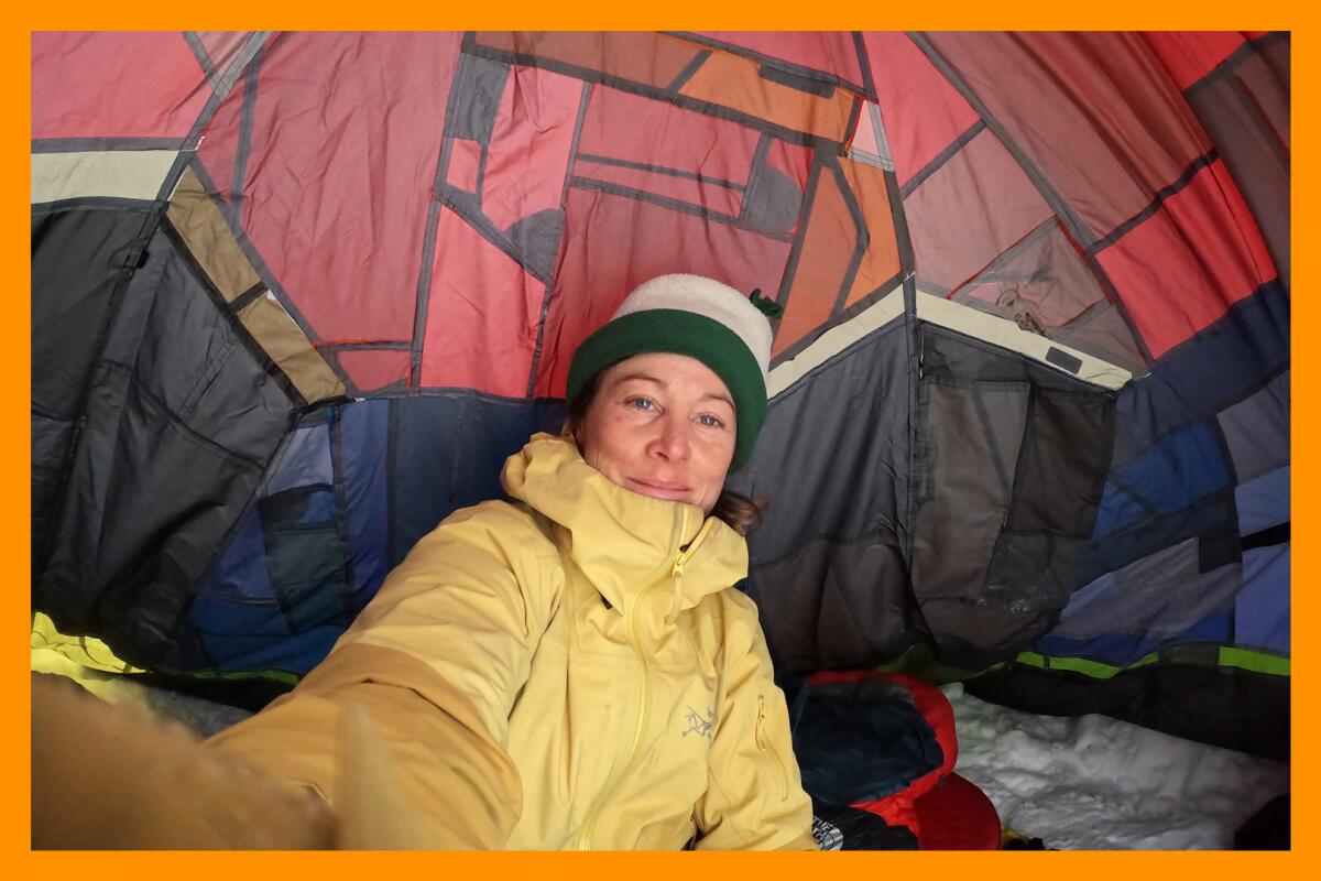 A woman takes a selfie inside a tent.
