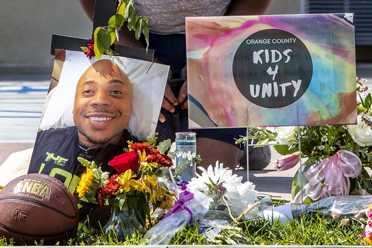 A makeshift memorial for Kurt Reinhold shows flowers, a photo and a basketball on grass