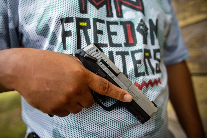 MINNEAPOLIS, MN - JULY 25: Romeal Taylor, a member of the Minnesota Freedom Fighters, sheds his riffle and tactical vest, only carrying a hand gun, at the meet-and-greet event to connect with the community on Saturday, July 25, 2020 in Minneapolis, MN. (Jason Armond / Los Angeles Times)
