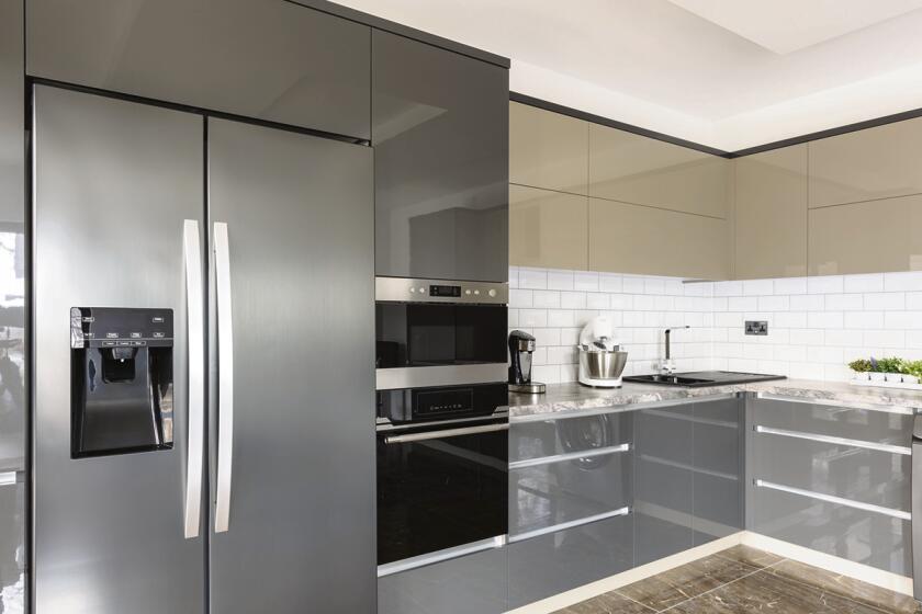 Spacious luxury well designed modern grey, beige and white kitchen withdouble sized fridge. Door of electric oven is open