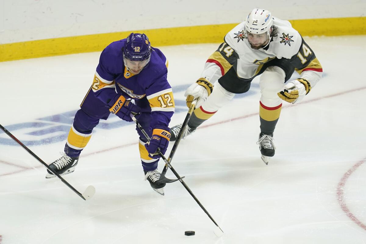 Kings center Trevor Moore and Vegas Golden Knights defenseman Nicolas Hague reach for the puck.