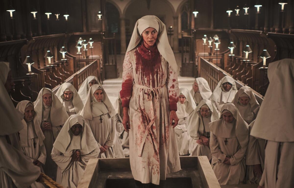 A woman in white nun's outfit covered in blood, surrounded by other nuns 